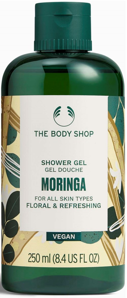 A green bottle of The Body Shop Moringa shower gel with a beige, green, and gold floral design label.