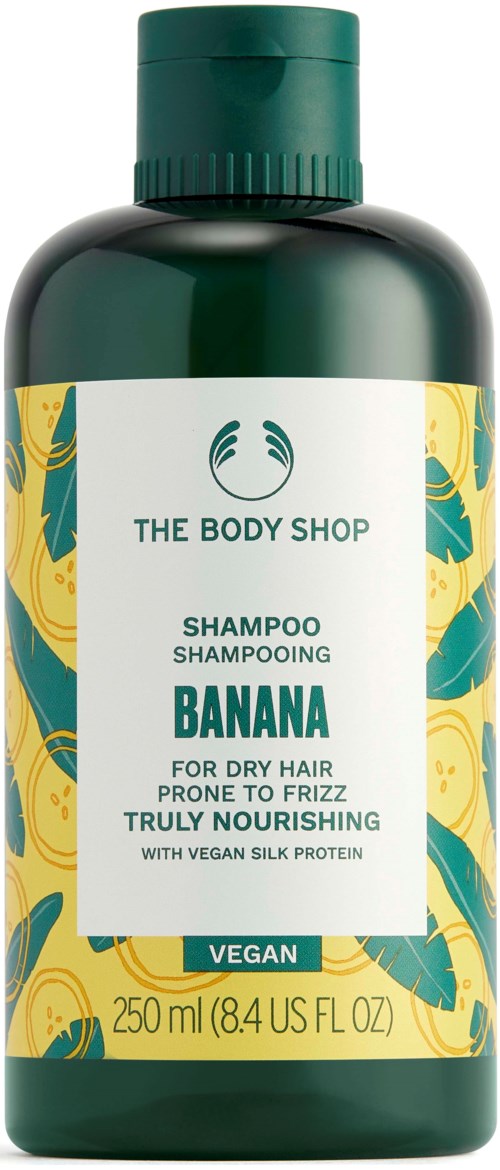 Grön schampoflaska med gul och grön bananbladdesign, märkt "Banana" för torrt, frissigt hår, vegansk, näringsrik.