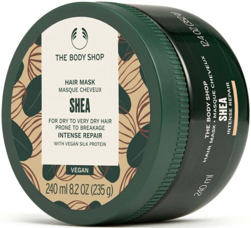 Ein dunkelgrüner Behälter von The Body Shop Shea Hair Mask mit Naturblatt-Design und Produktdetails.
