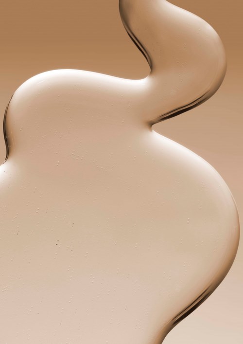 Eine Schleife aus hellbeigem Crem oder Lotion mit glatter Textur, die sanft fließt.