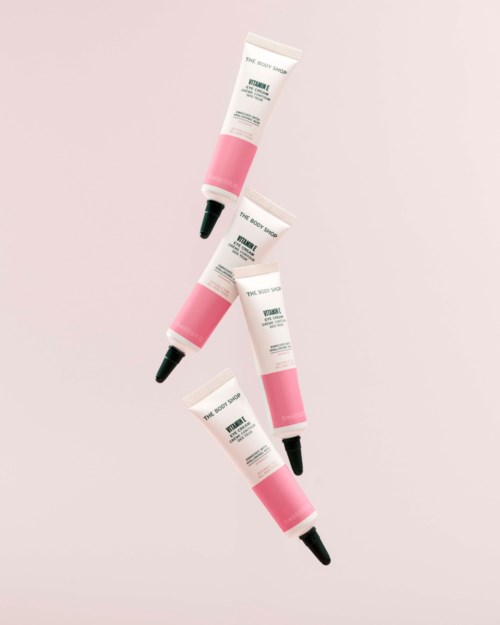 Four tubes of skincare product with pink and white packaging and black applicator tips arranged diagonally on a light background.