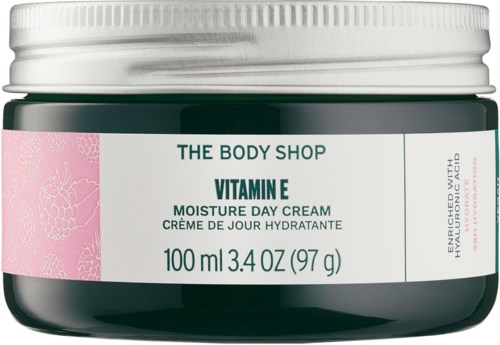 Ein Behälter von The Body Shop Vitamin E Moisturizer Day Cream, 100 ml, grüner Behälter mit rosa Etikett und weißem Deckel.