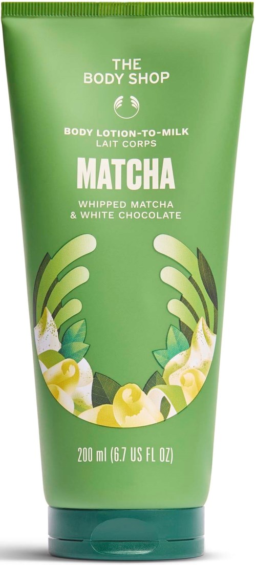 Vihreä Puteli The Body Shop Matcha vaahdotettu vartalovoide lehtien ja valkoisten kukkien kanssa.