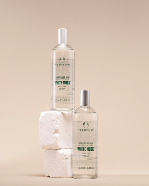 To parfyme sprayflasker merket White Musk plassert på hvite blokker mot en myk beige bakgrunn.