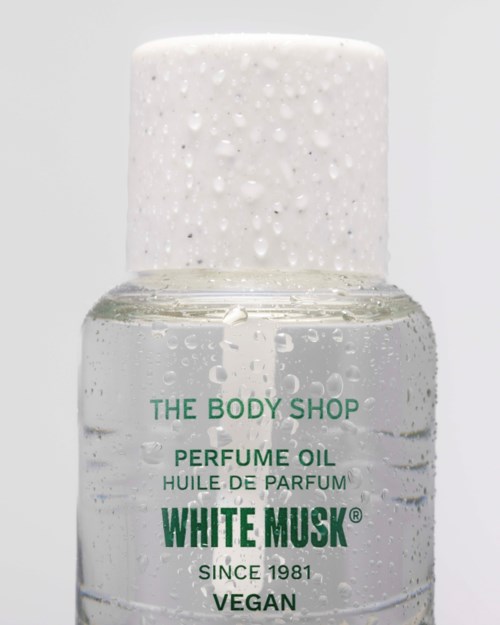 Bottle of perfume oil from The Body Shop, labeled White Musk, vegan, with a white cap and clear liquid inside.
