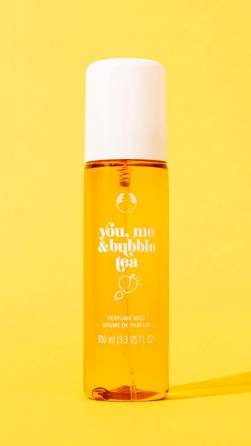 Eine kleine orange Sprühflasche mit weißem Deckel vor gelbem Hintergrund.