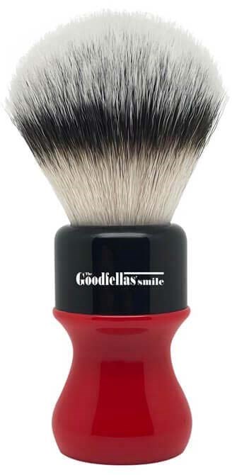 A shaving brush with black, white, and gray bristles and a red handle.