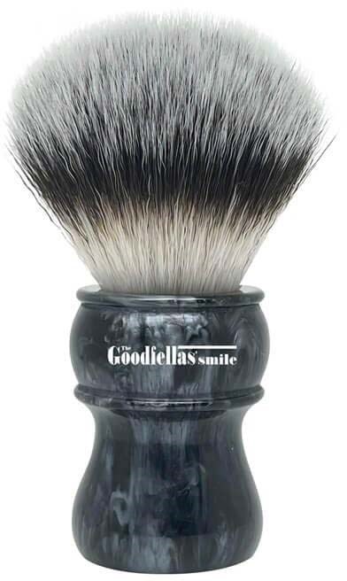 A shaving brush with black and white bristles in a dark handle, labeled 'The Goodfella's Smile.'