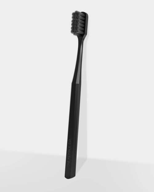 A black toothbrush with a curved handle and brush head, standing upright against a plain background.