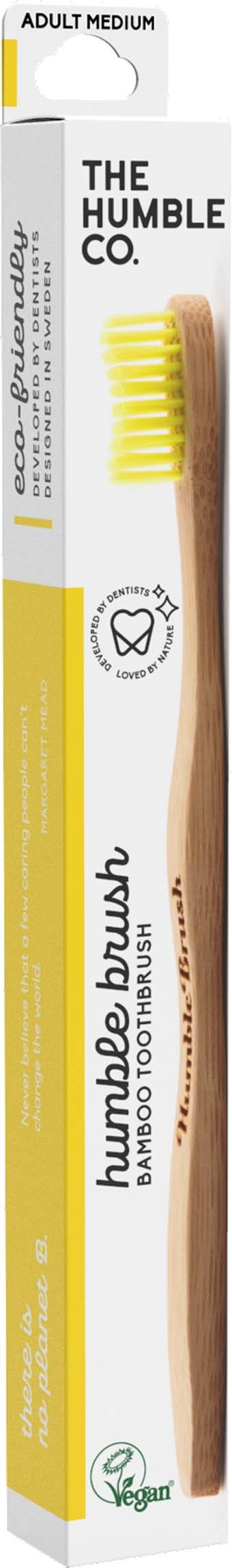 Eine braune Bambuszahnbürste mit gelben Borsten in einer weißen und gelben Verpackung mit der Aufschrift "The Humble Co.".