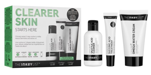 A skincare set with cream and treatment in white bottles, featuring black and white packaging, and a green box with text.