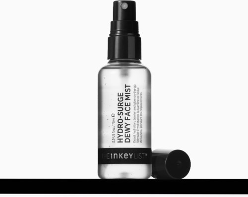 A clear spray bottle labeled Hydro-Source Dewy Face Mist with a black cap lies next to it.