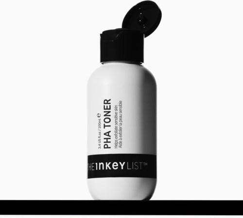 Een klein witte fles met een zwarte deksel en zwart etiket, gelabeld Phat toner en The Inkey List.