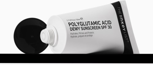 Een tube zonnebrandcrème met een zwarte dop, gemarkeerd 'POLYGLUTAMIC ACID DEWY SUNSCREEN SPF 30', liggend op een oppervlak.