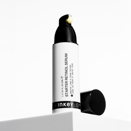 A skincare product bottle with a black lid and a small amount of yellowish cream on top.