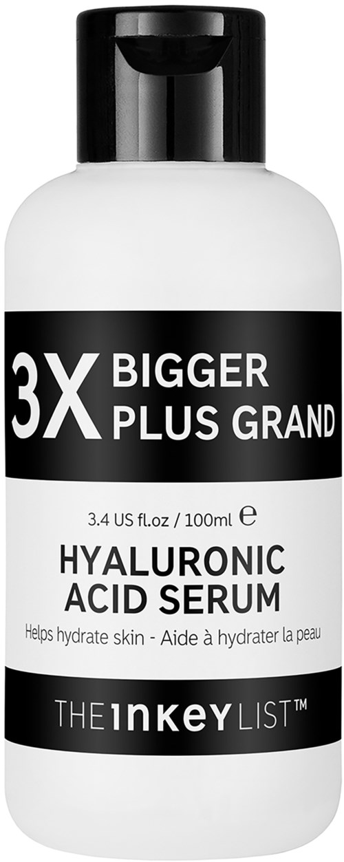 En vit flaska med svart etikett; nämner hyaluronsyra serum som hjälper till att återfukta huden, med extra fokus på "3X Bigger Plus Grand."