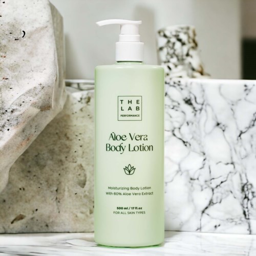Vaaleanvihreä pullo Aloe Vera Body Lotionia marmorin päällä, pumppu ja tuotteen kuvaus.
