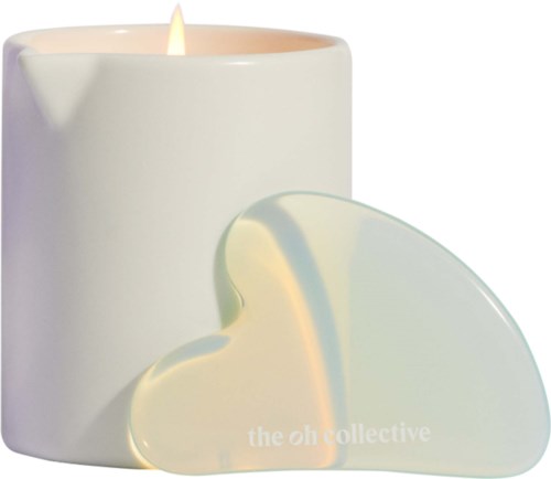 A lit candle next to a heart-shaped object with the text 'the oh collective' on it.