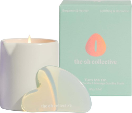 A white candle with a soft glow, heart-shaped soap, and pastel green box with a logo and text.