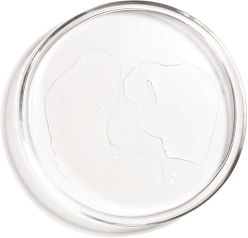 A clear, round glass container with a white liquid inside, possibly water, seen from above.