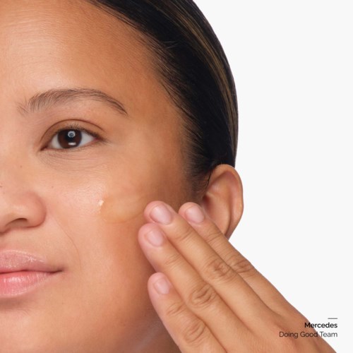 A woman touches her face gently, showing her skin with natural beauty and clear complexion.