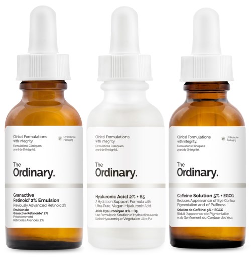 Three small brown and white bottles with droppers, labeled with skincare product names and descriptions.
