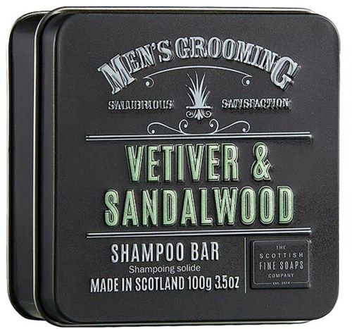 A black grooming product tin with green and white text for men's shampoo, vetiver and sandalwood scent, made in Scotland.
