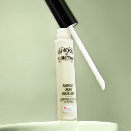 Een witte vloeibare lippenstift met zwart deksel, gemerkt "Department of Corrections" en "Redness Color Corrector."