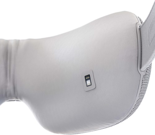 Een wit kussen met een klein apparaatje bevestigd, mogelijk een slaaptracker of sensor.