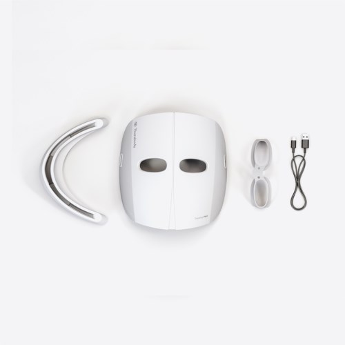 Een witte hoofdmasker, hoofdband, USB-opladingskabel en een klein doosje met spiegel.