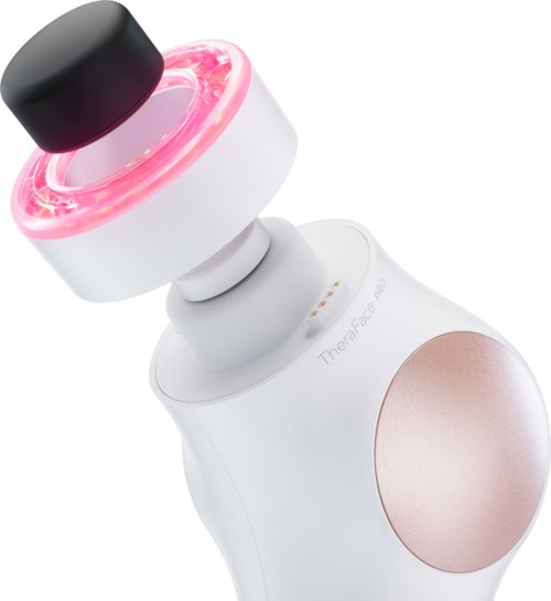 Een witte huidverzorgingsapparaat met een zwarte bovenkant en roze lichtring, met een grote roségouden cirkel op het lichaam.