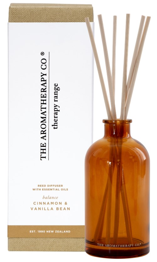 A brown glass bottle with reed sticks, next to a white box with text about aromatherapy and essential oils.