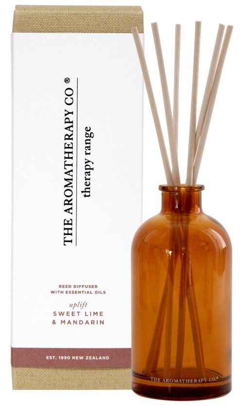 A brown glass bottle contains reed diffusers with sticks, and the box mentions essential oils with sweet lime and mandarin.