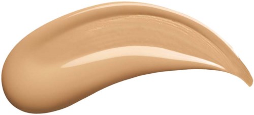 Eine beige Creme oder Foundation in einer gebogenen Form. Sie sieht dick und glatt aus, auf einem schwarzen Hintergrund.