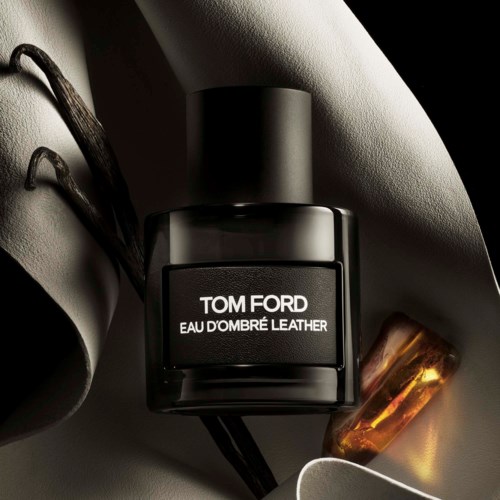 Zwarte Tom Ford parfumfles met witte tekst en een goudkleurig object in de buurt in een stijlvolle setting.