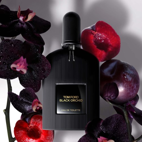 Een fles Tom Ford Black Orchid parfum omgeven door donkerpaarse en rode bloemen met waterdruppels.