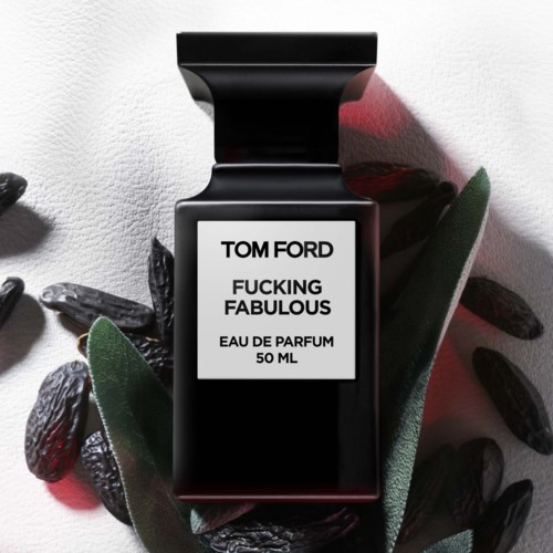 A black perfume bottle labeled 'Tom Ford Fucking Fabulous' surrounded by dark stones and green leaves.