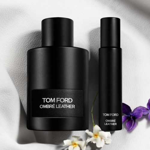 Zwei schwarze Flaschen mit Tom Ford Ombré Leather-Parfüm, daneben Blumen.