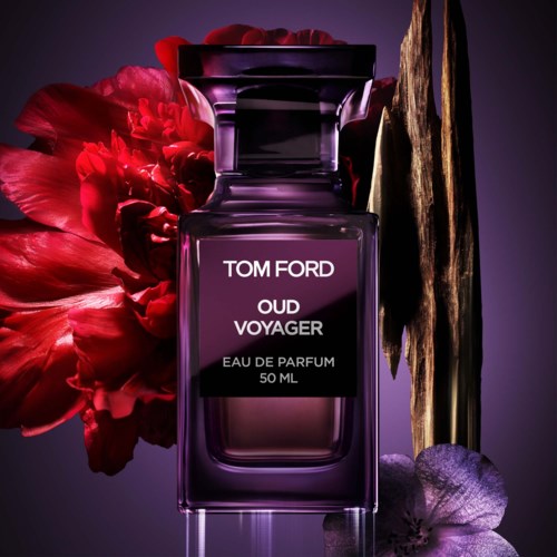 En Tom Ford Oud Voyager parfymflaska med lila gradient, omgiven av en röd blomma och ett gyllene dekorativt element.