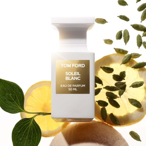 This is a perfume bottle surrounded by lemon slices and green leaves, with some herbs or seeds sprinkled around.