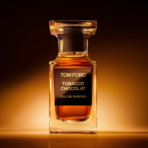 Perfume bottle with a black label reading Tom Ford Tobacco Chocolat, set against a warm, gradient background.