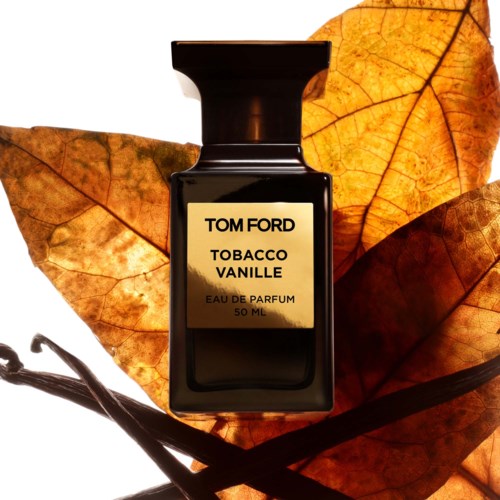 A black perfume bottle labeled 'Tom Ford Tobacco Vanille' on orange and brown autumn leaves.