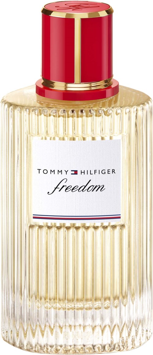 En høy parfymeflaske med ribbet glasskropp, en hvit etikett og en gull- og rød hette. Etiketten sier Tommy Hilfiger freedom.