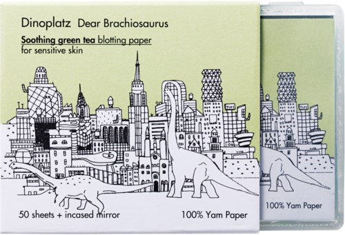Eine grüne Verpackung für beruhigendes grünes Tee-Puderpapier mit Stadt und Dinosaurier-Illustrationen.