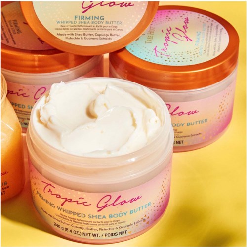 Offener Topf mit cremigem Sheabutter und pink, orange sowie gelber Beschriftung, zeigt glatte weiße Butter im Innern.