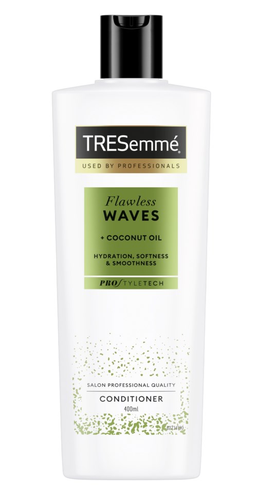 A white bottle of TRESemmé conditioner with a black cap, labeled 'Flawless Waves' with coconut oil, for soft, smooth hair.