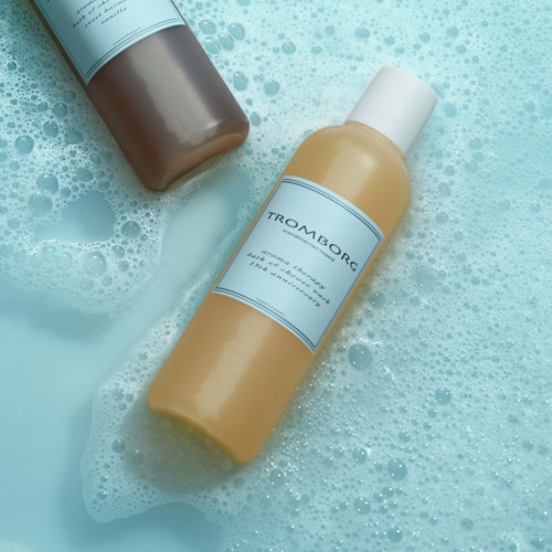 Zwei Flaschen Shampoo oder Duschgel in schäumiger, blauer Umgebung. Ein ist beige, der andere ist braun.