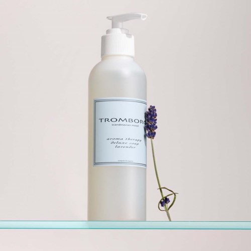 Eine weiße Flasche mit Pumpe, beschriftet 'TROMBOR' und Lavendelblumen daneben.