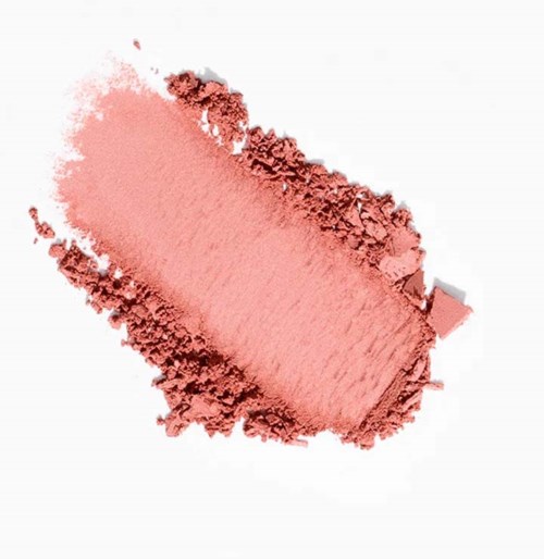 A pink powder spread out with some scattered pieces on a white background.