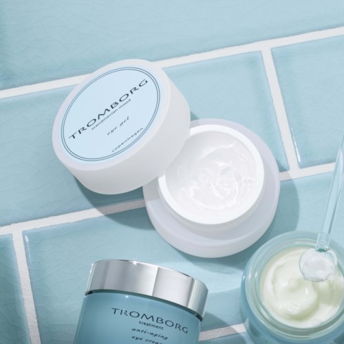 Hautpflegeprodukte, darunter Creme in einem Glas und Behandlung in einer Tube, sind auf einer Fliesenfläche gezeigt.